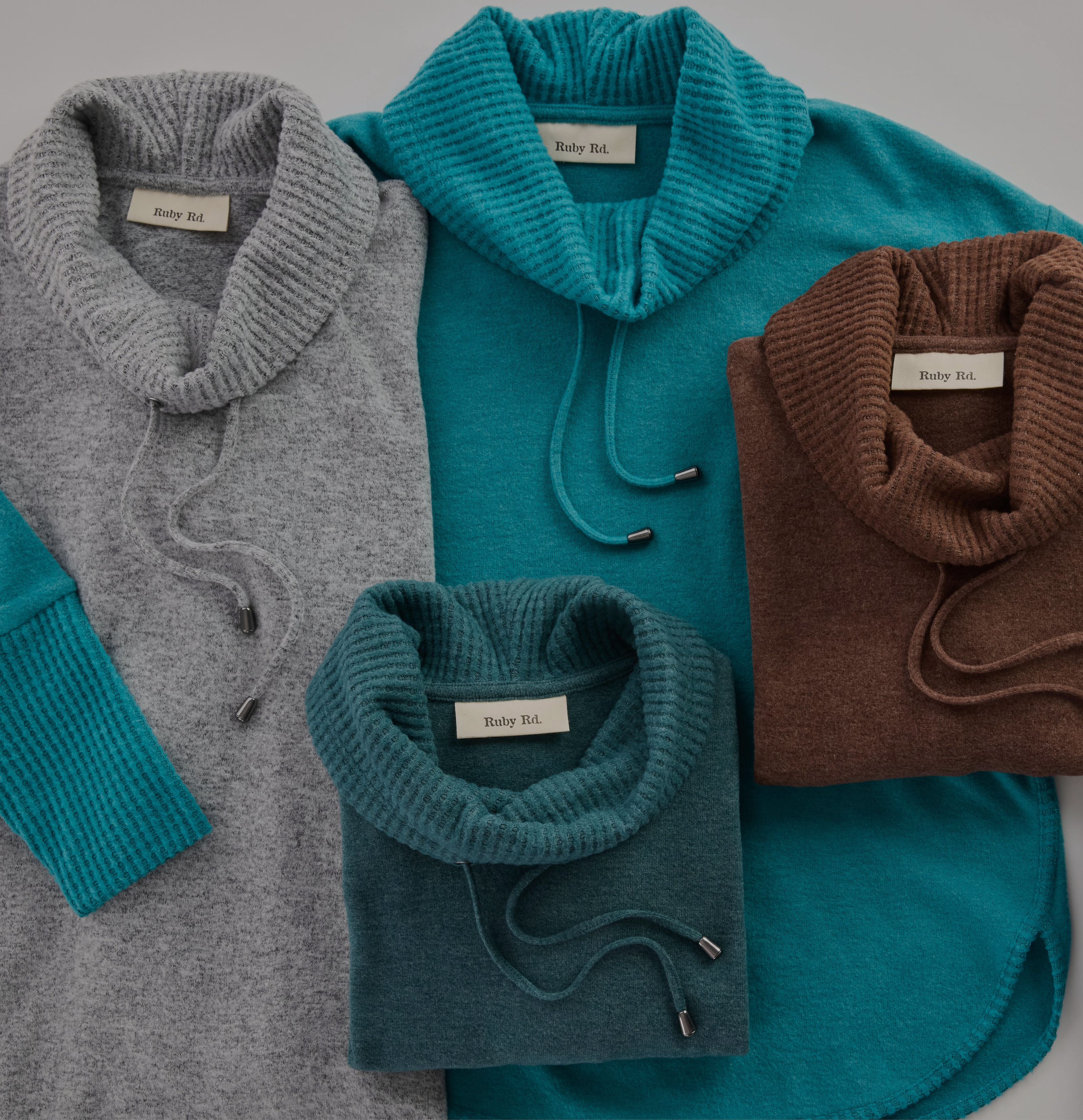 Four cozy sweaters in gray, teal, and brown arranged on a gray background.