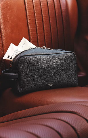A black leather bag resting on a brown leather seat.