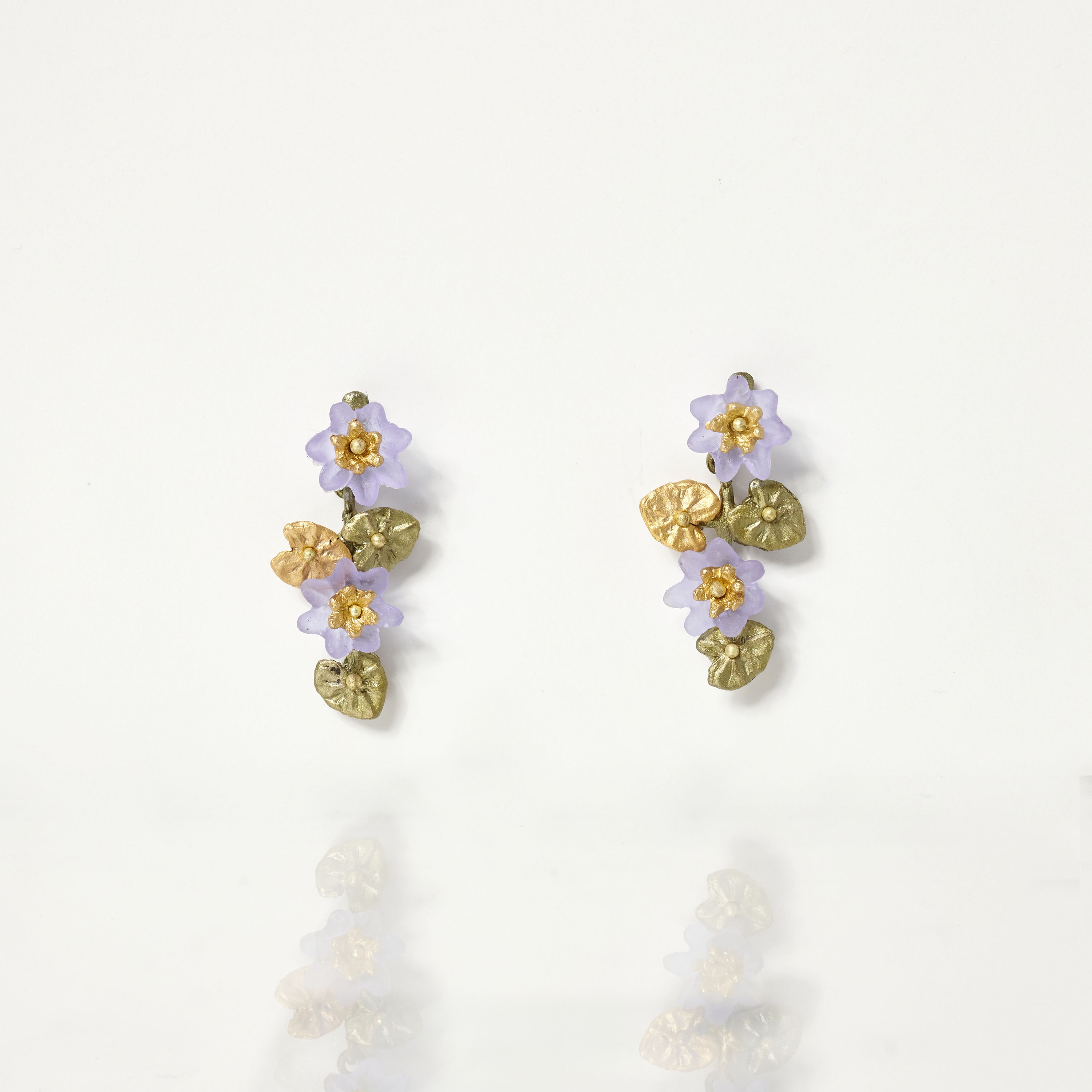 Floral earrings with purple flowers and gold leaves on a white background.