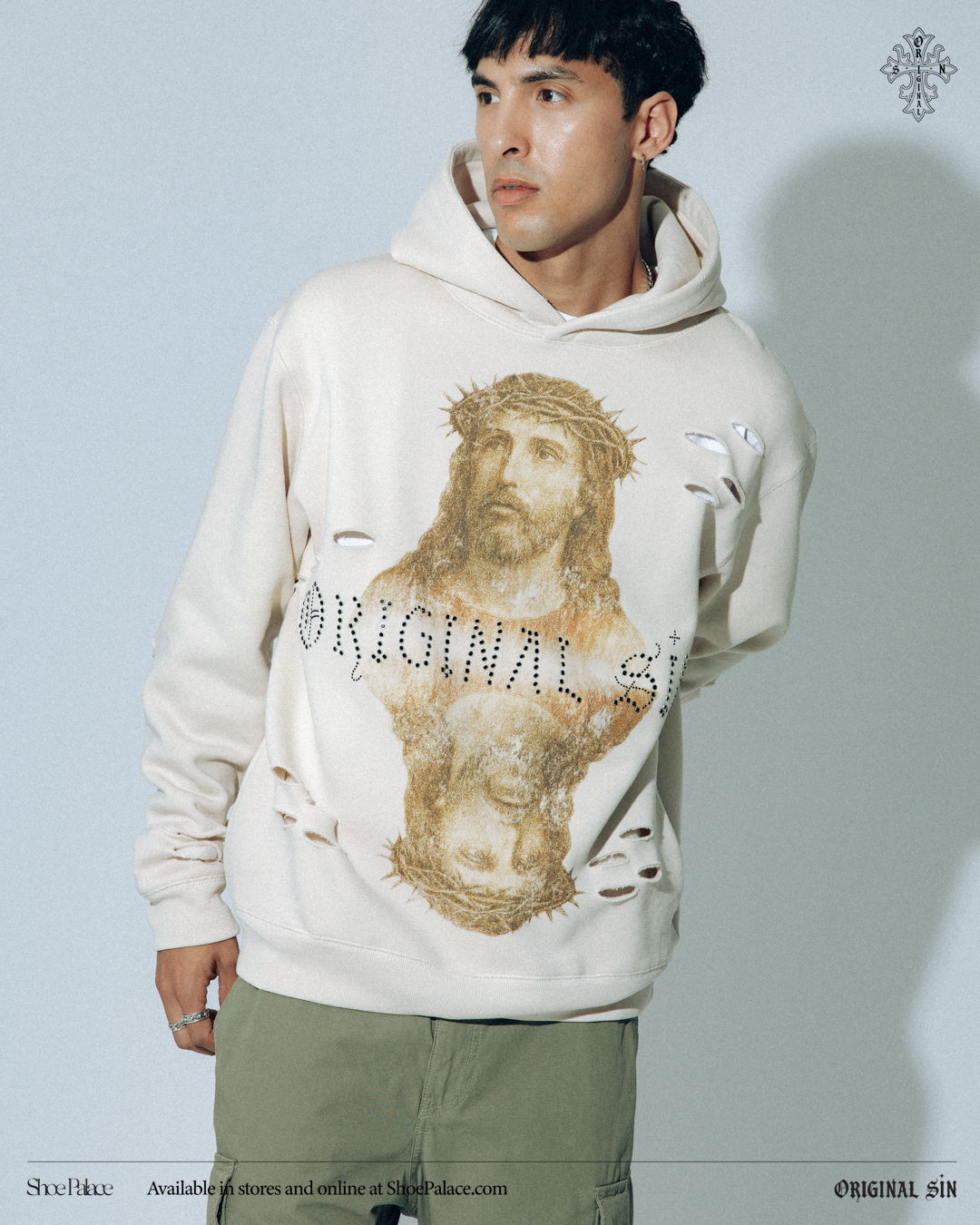 Person wearing a distressed hoodie with religious imagery and text.