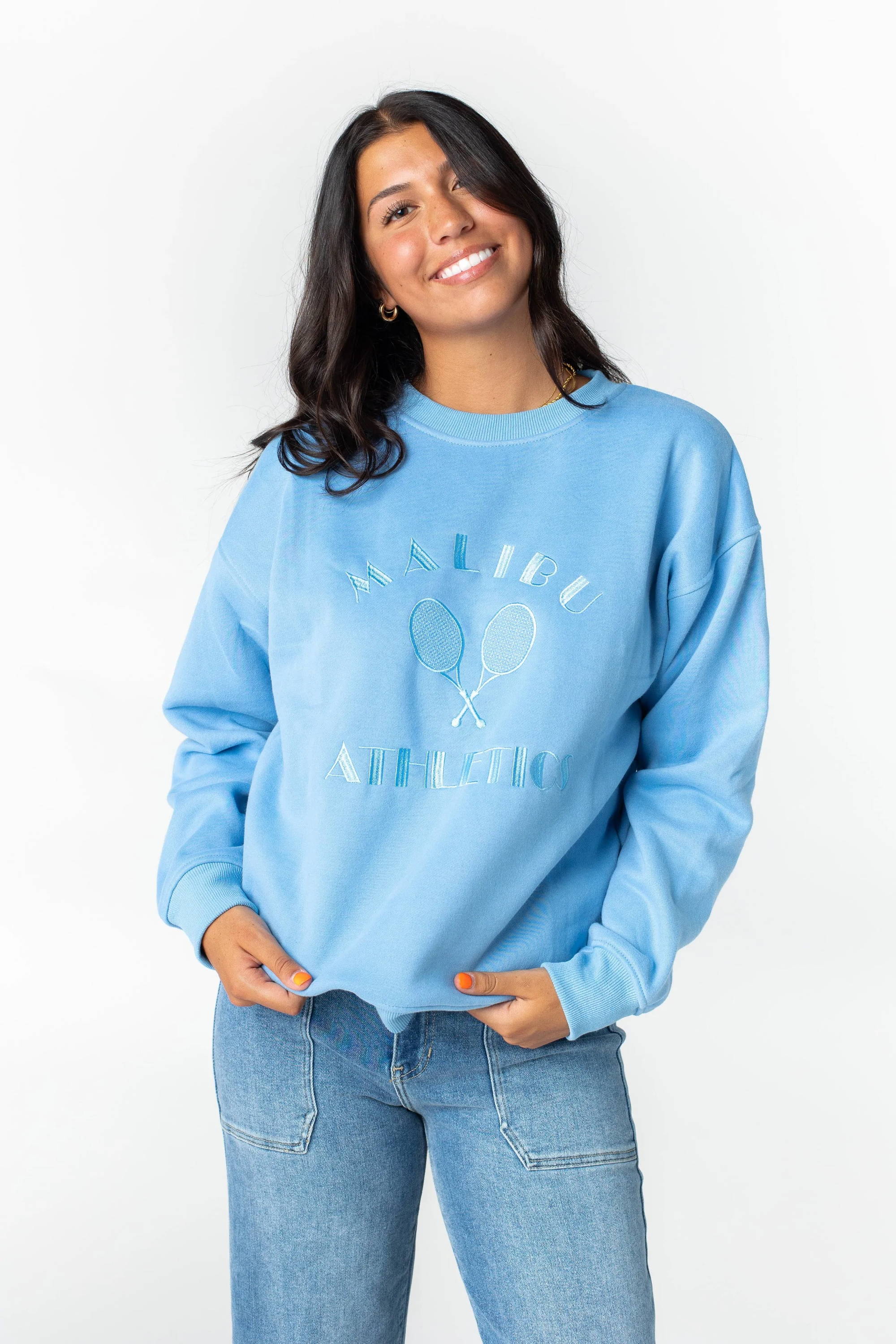 A woman poses in a blue sweatshirt and jeans