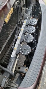 Close-up of four black train horns mounted on an aluminum bracket behind the front bumper