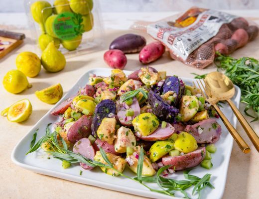 Colorful potato salad with herbs, lemons, and a side of fresh ingredients.