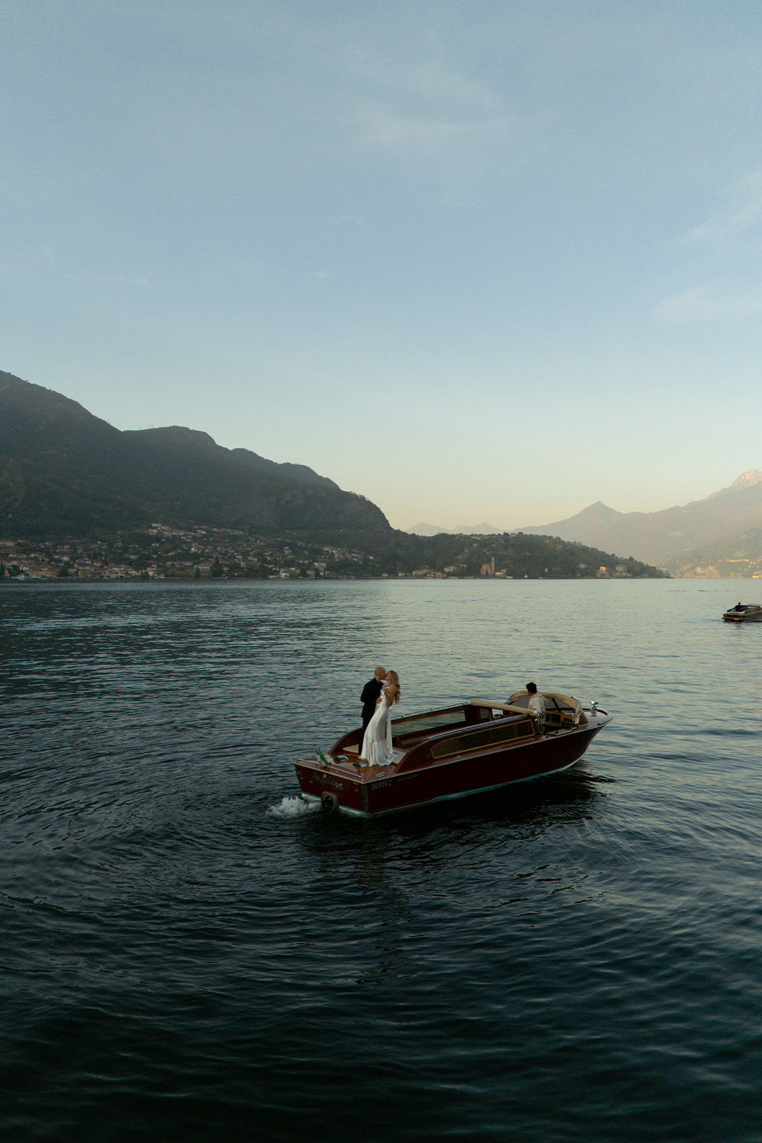 A couple in a boat on calm water surrounded by mountains.