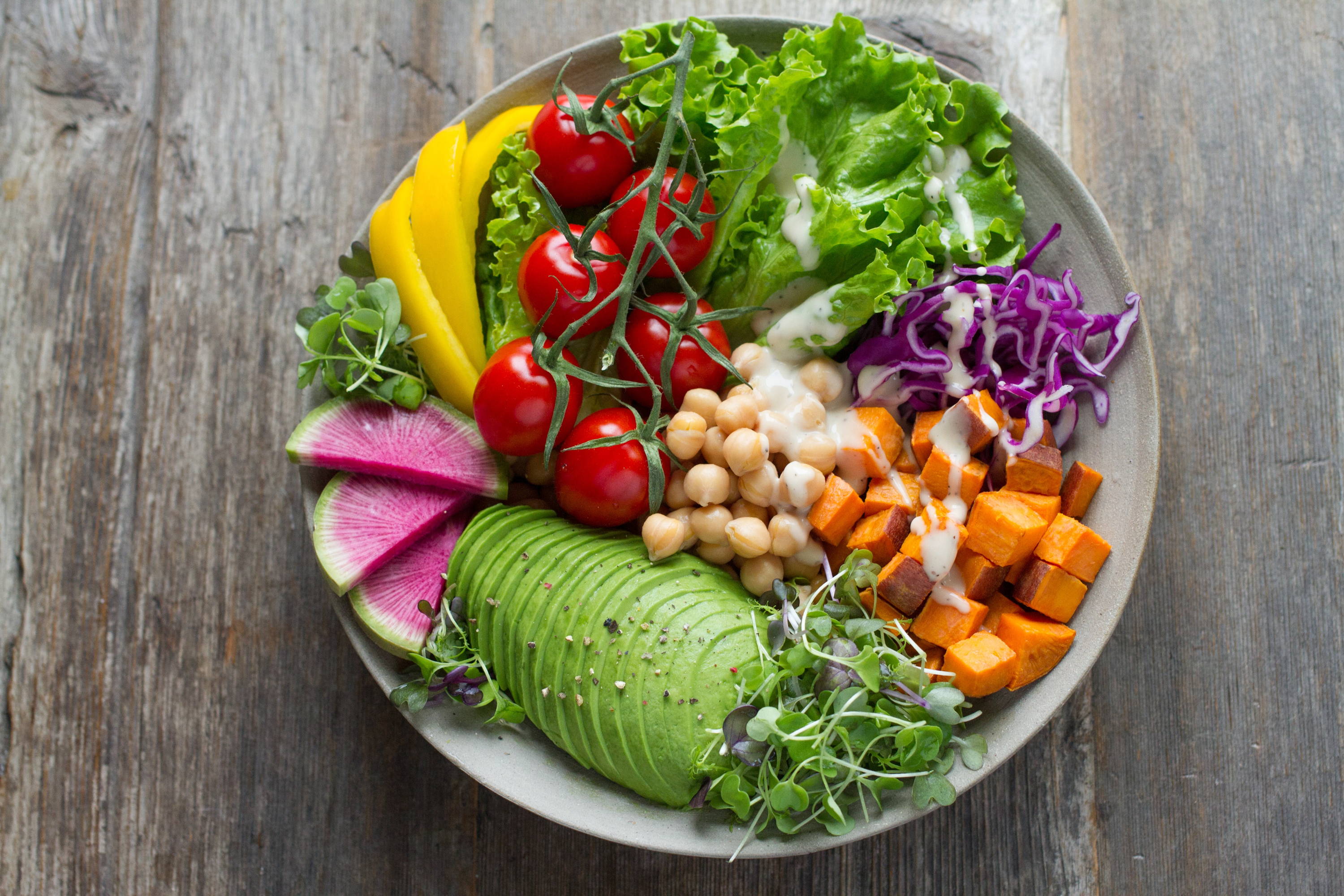 plant based salad plate with avocado lettuce tomatoes radishes yellow pepper cabbage, sweet potatoes and garbanzo beans