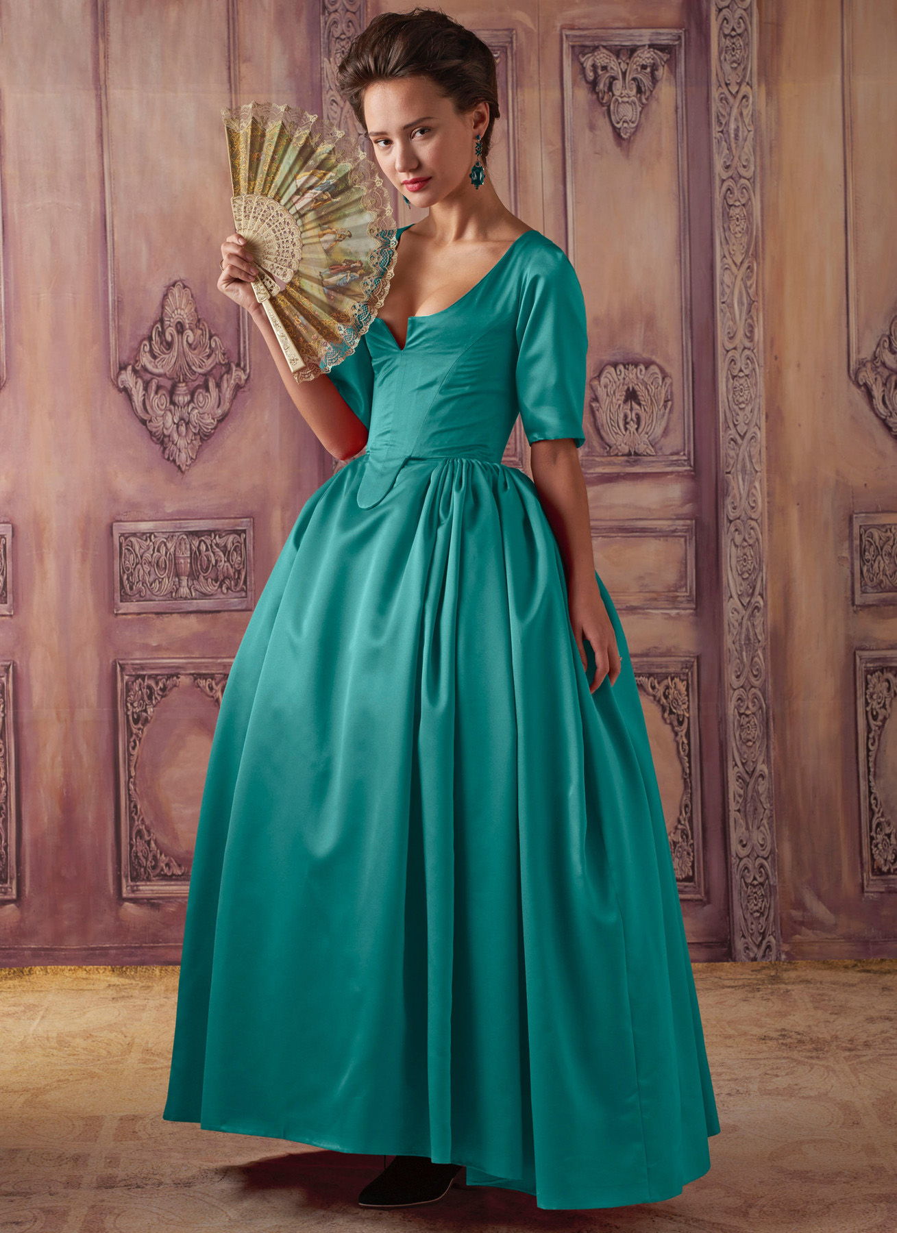 Woman in a teal gown holding a fan, standing in an elegant setting.