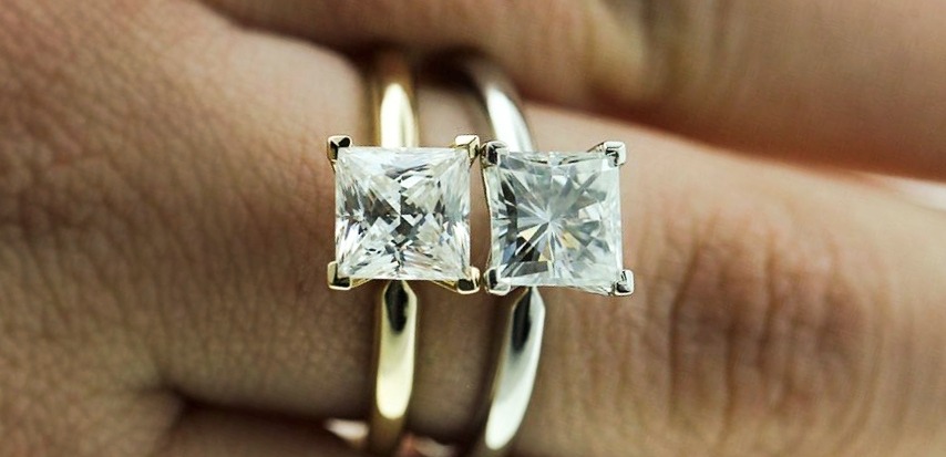 Moissanite set in an engagement ring next to a diamond hybrid simulant set in an engagement ring for comparison