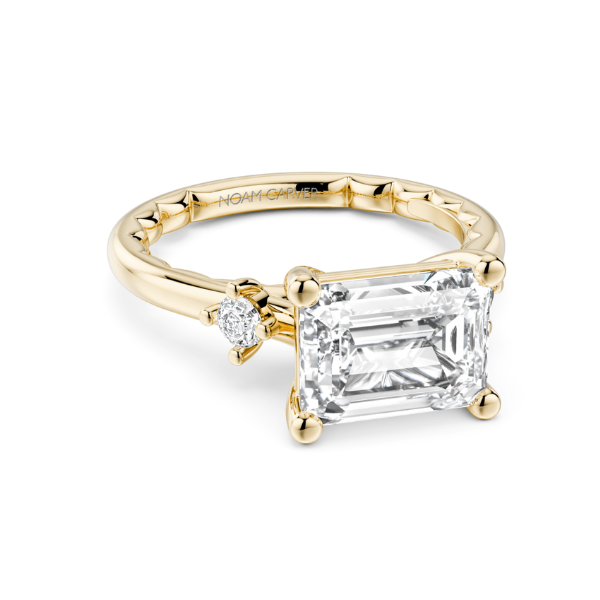Gold ring with a large emerald-cut diamond and smaller accent stones.
