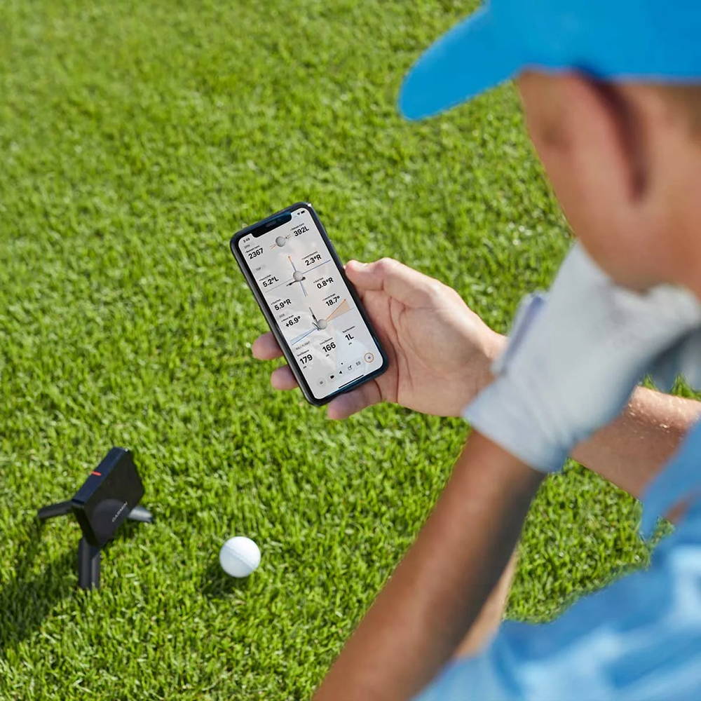A golfer looking at the data on his smartphone over the Garmin Approach R10 launch monitor
