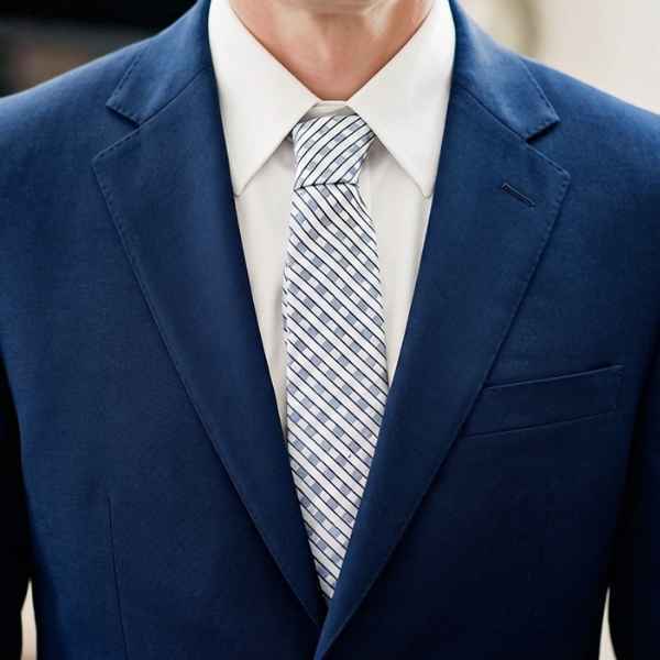 Man wearing a blue gingham like plaid tie with a navy blue suit