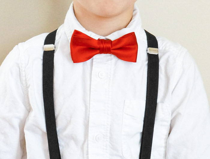 Boy wearing a red solid bow tie and black suspenders