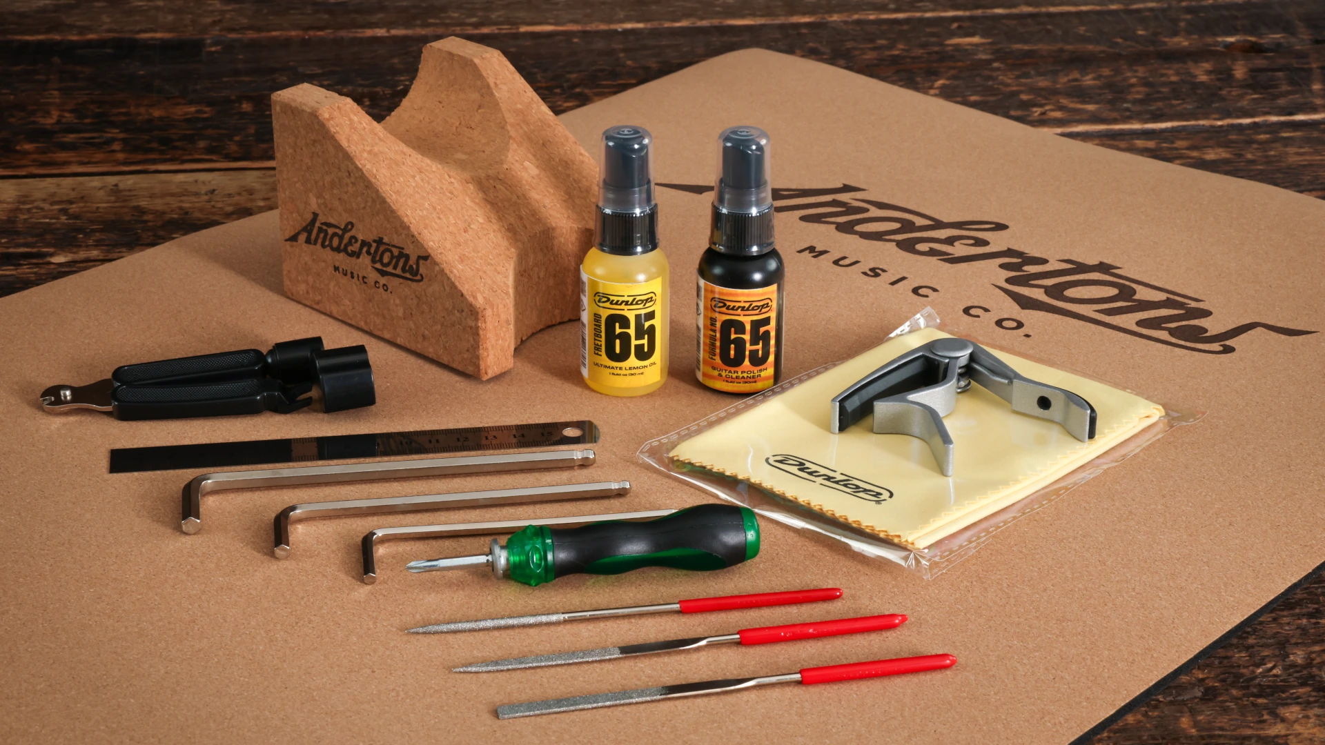 Assorted guitar tools and supplies arranged on a wooden surface.
