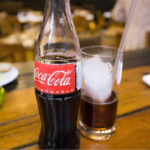 Glass bottle of Mexican Coke with a glass of ice