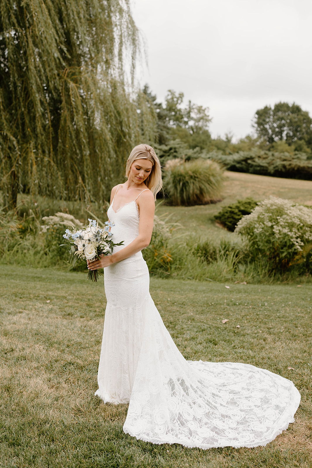 Bride in a strapless wedding dress holding a bouquet outdoors.