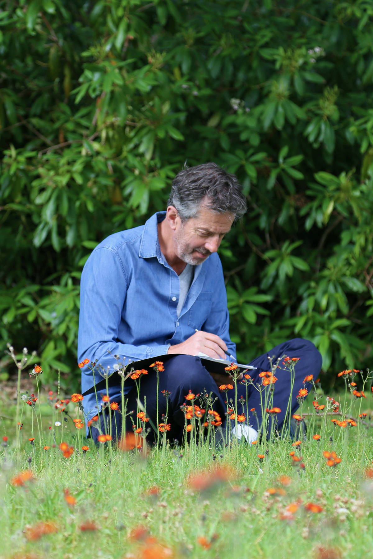Alex Monroe sat in a field drawing in his sketchbook.
