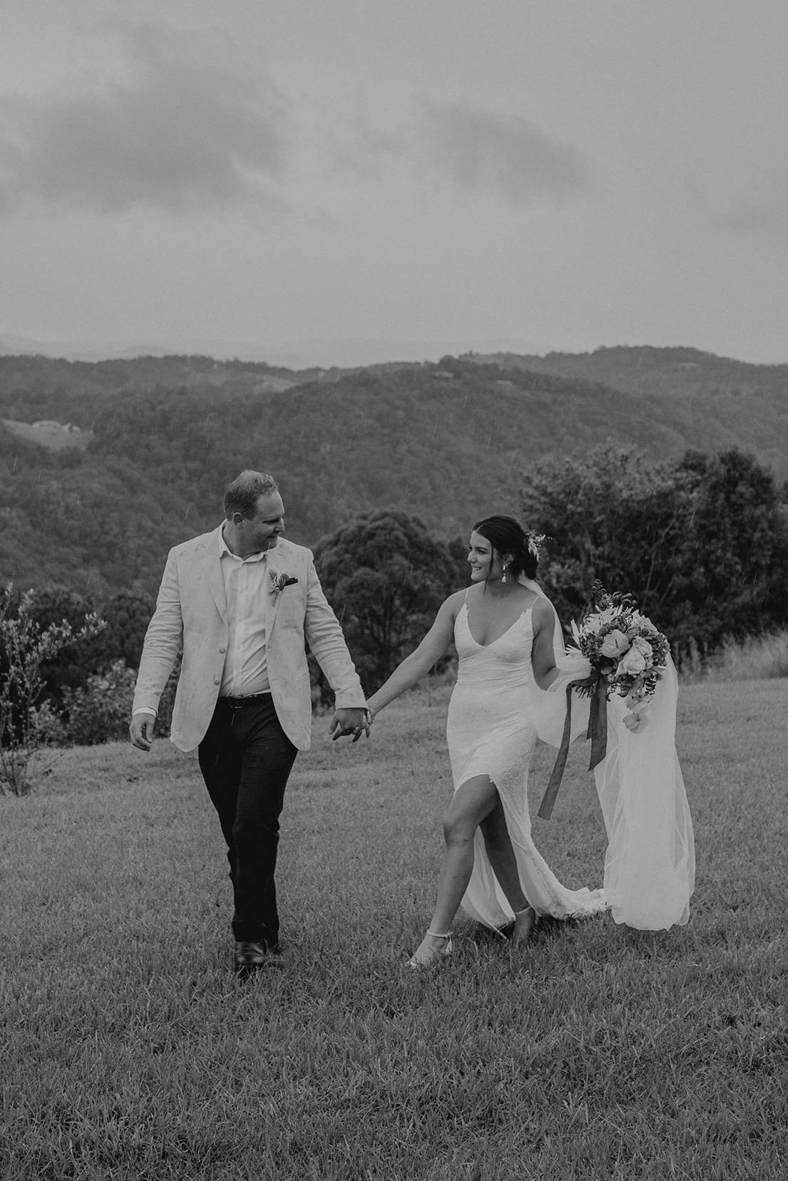 Bride wearing a white dress with front split walking with her groom outdoors