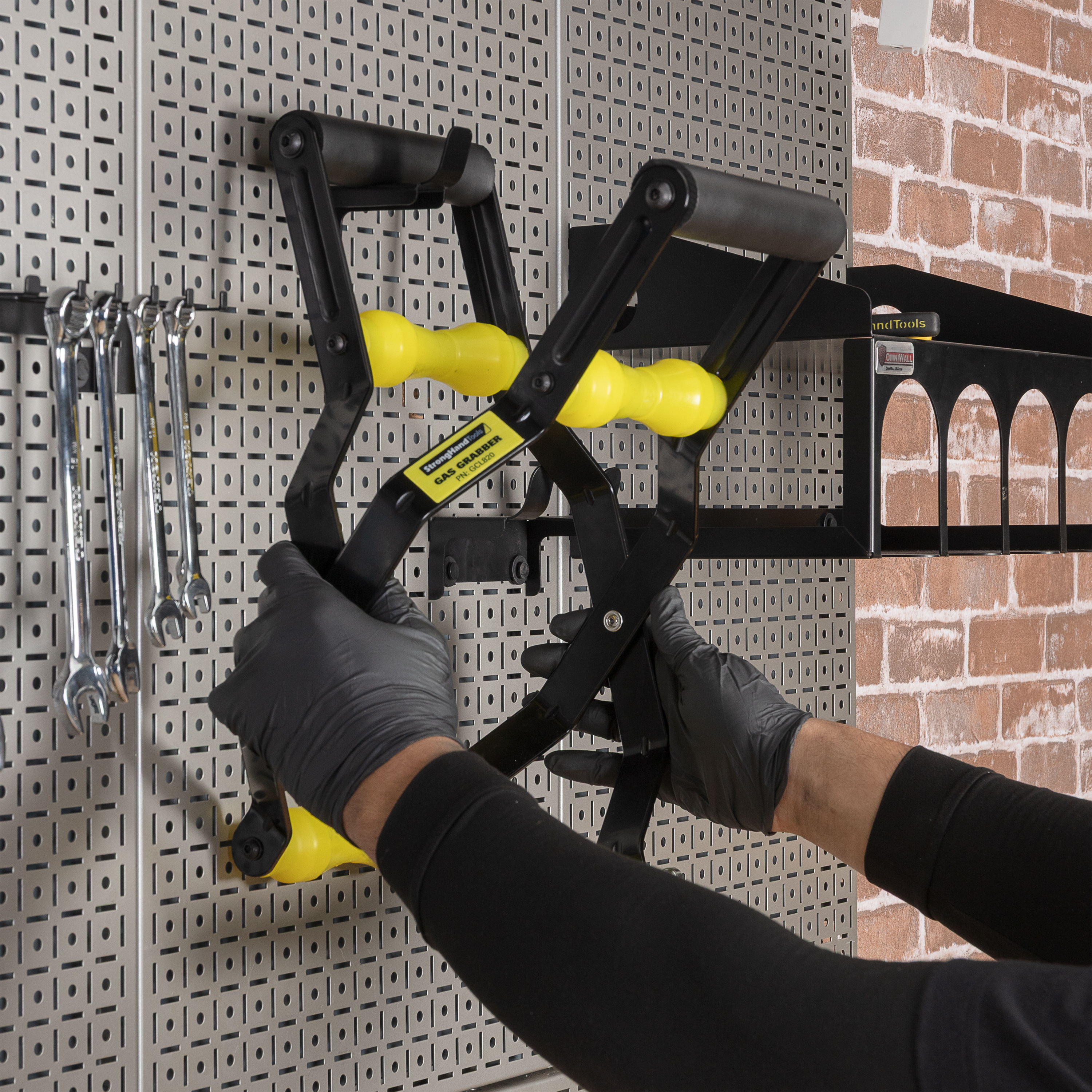 Person using a tool holder on a pegboard wall.