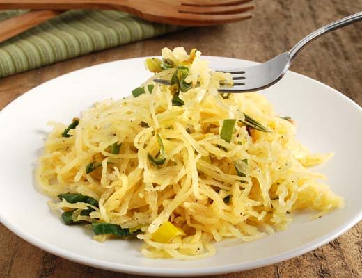 A plate of squash spaghetti with vegetables and a fork.