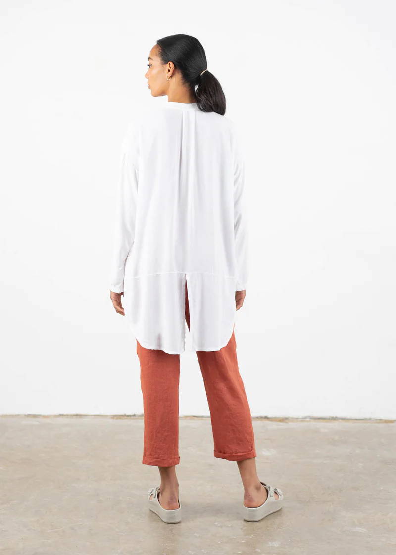 A model wearing a oversized white shirt with tux style dibbed hem, terracotta coloured cropped trousers and off white chunky platform slides