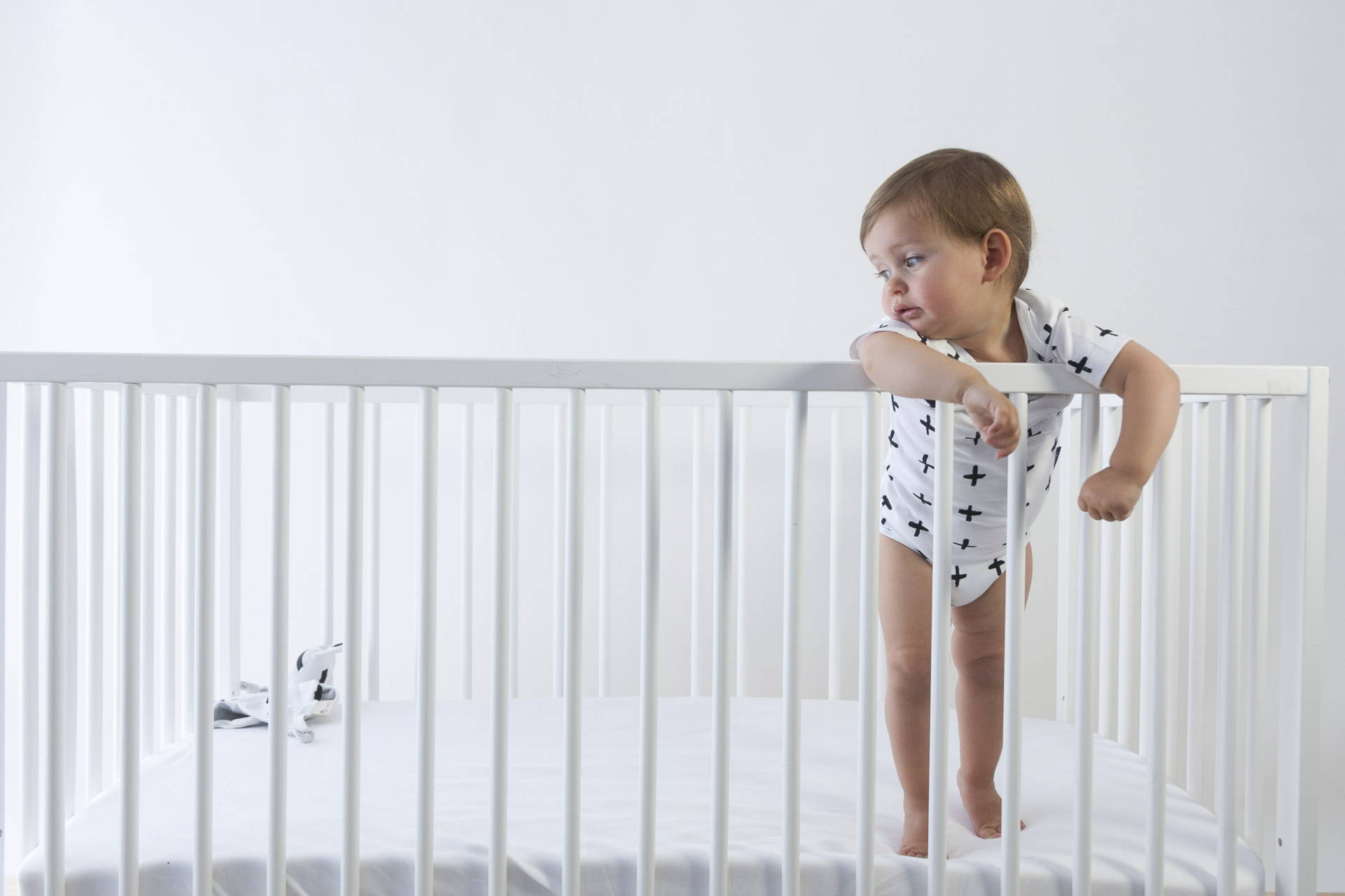 toddler standing in cot wearing cotton bodysuit