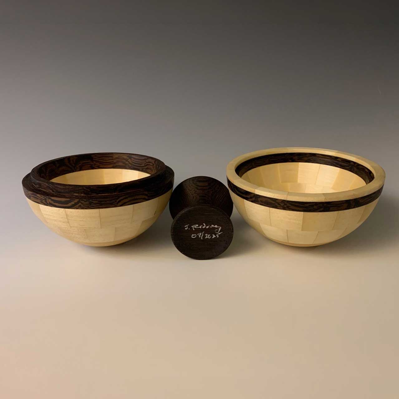 Two wooden bowls and a small wooden object on a gray background.