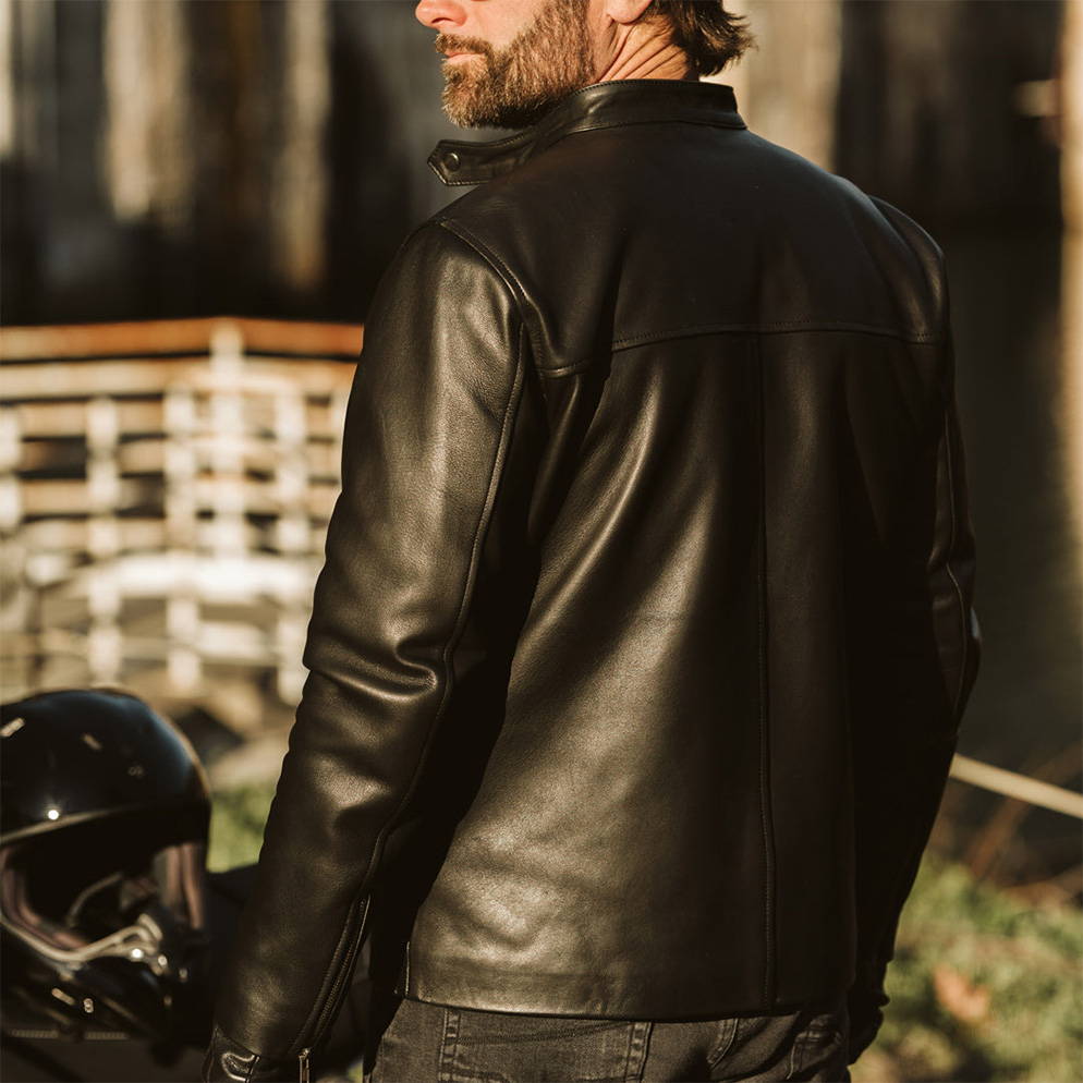 man standing with a motorcycle in a black leather jacket