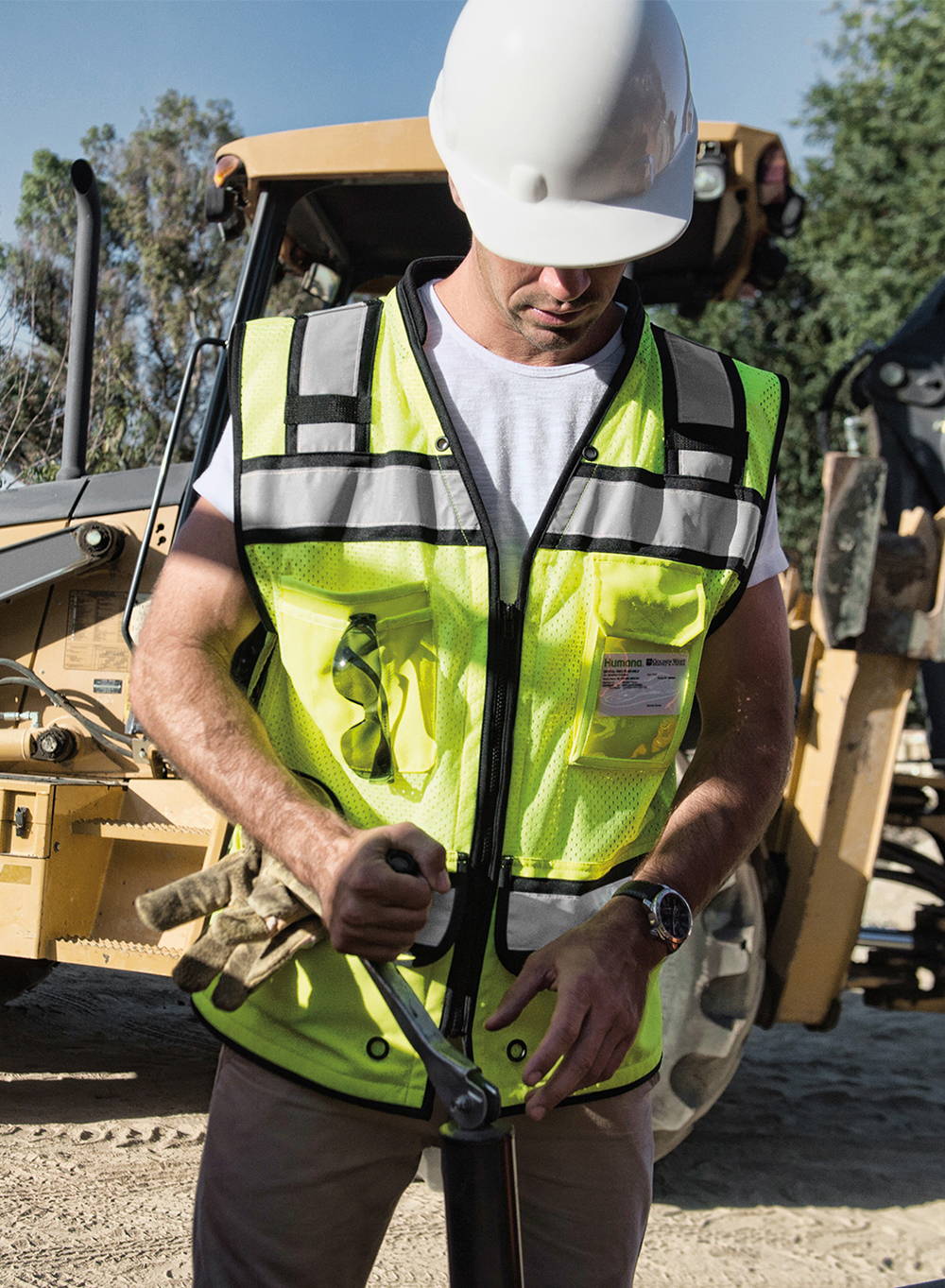 Construction worker wearing Hi-viz lime safety vest, and white hard hat.