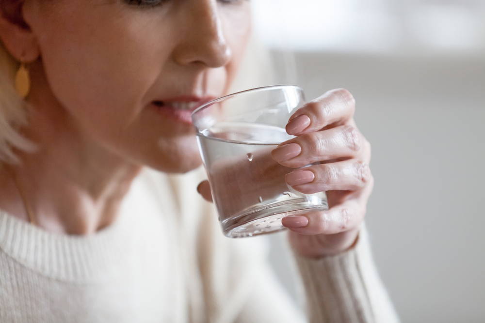 Elderly woman combats dehydration by drinking water