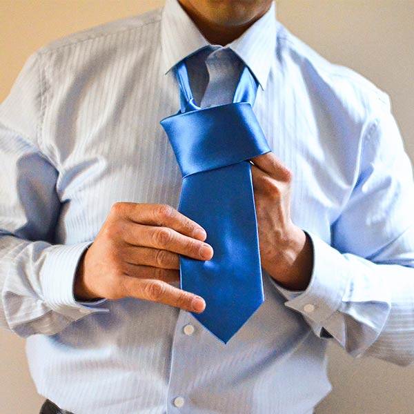 AI generated-like photo of a man tying a blue tie with too many fingers