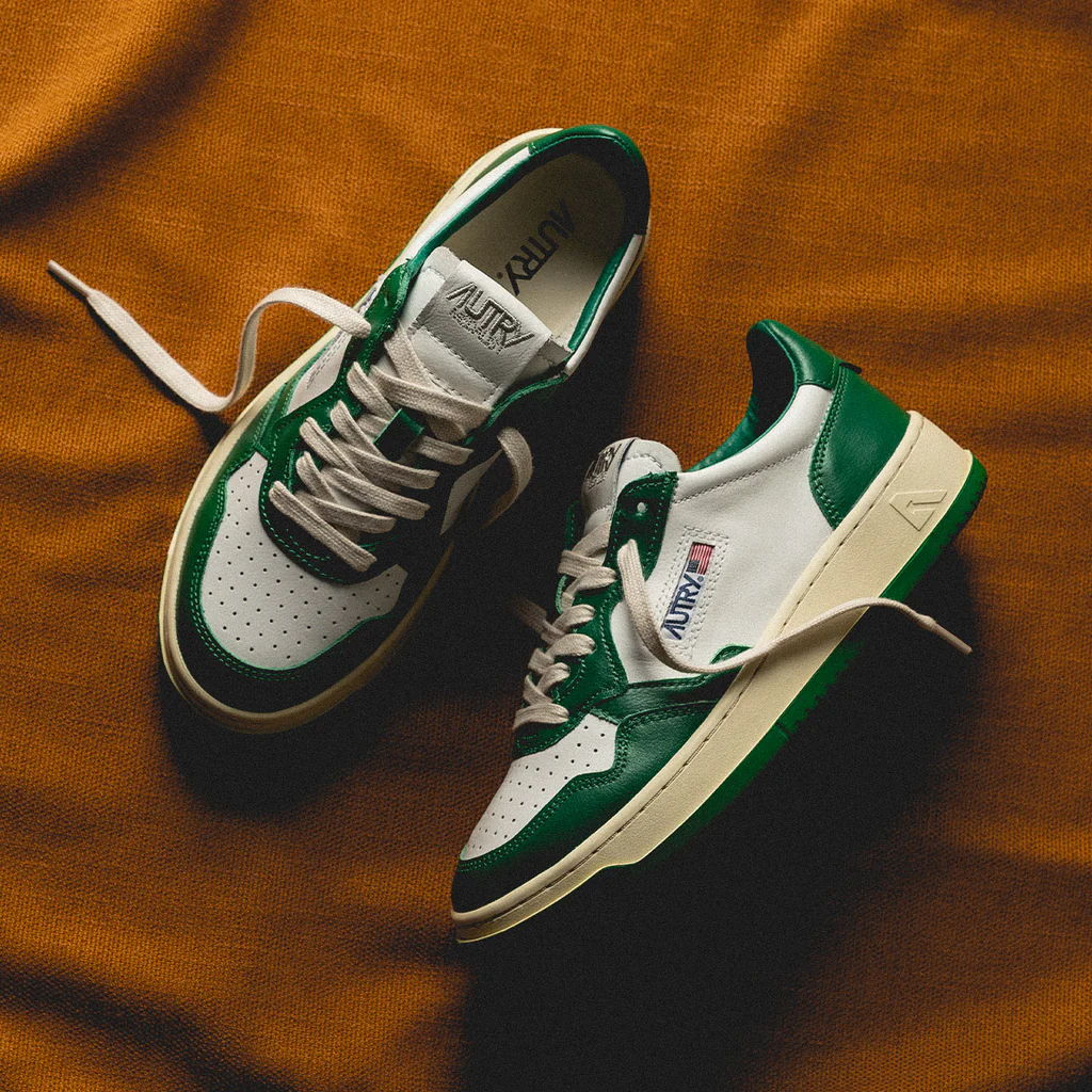 A pair of green and white sneakers on an orange background.