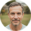 Man with short gray hair smiling outdoors.