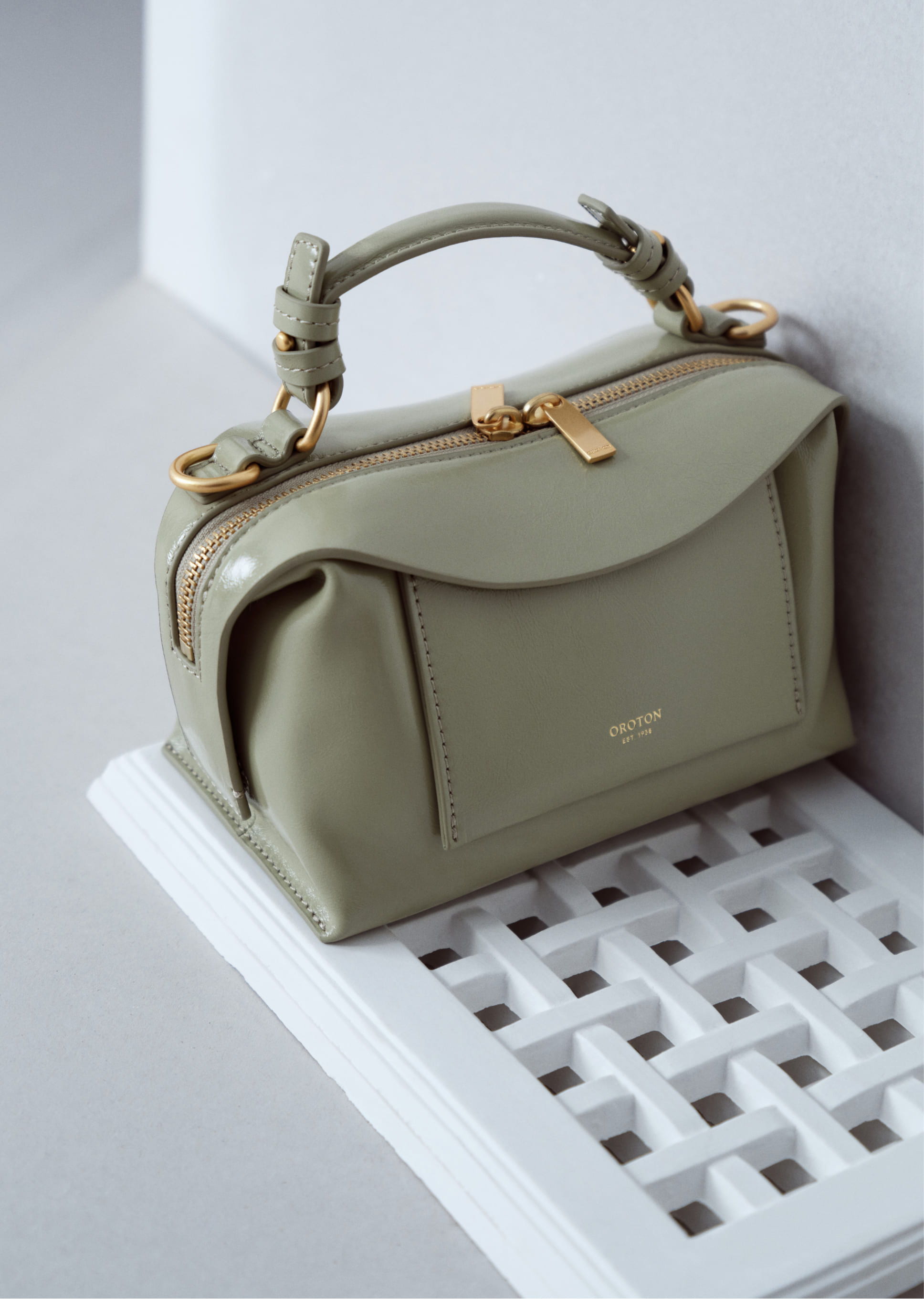 A stylish green handbag with a gold zipper on a white surface.
