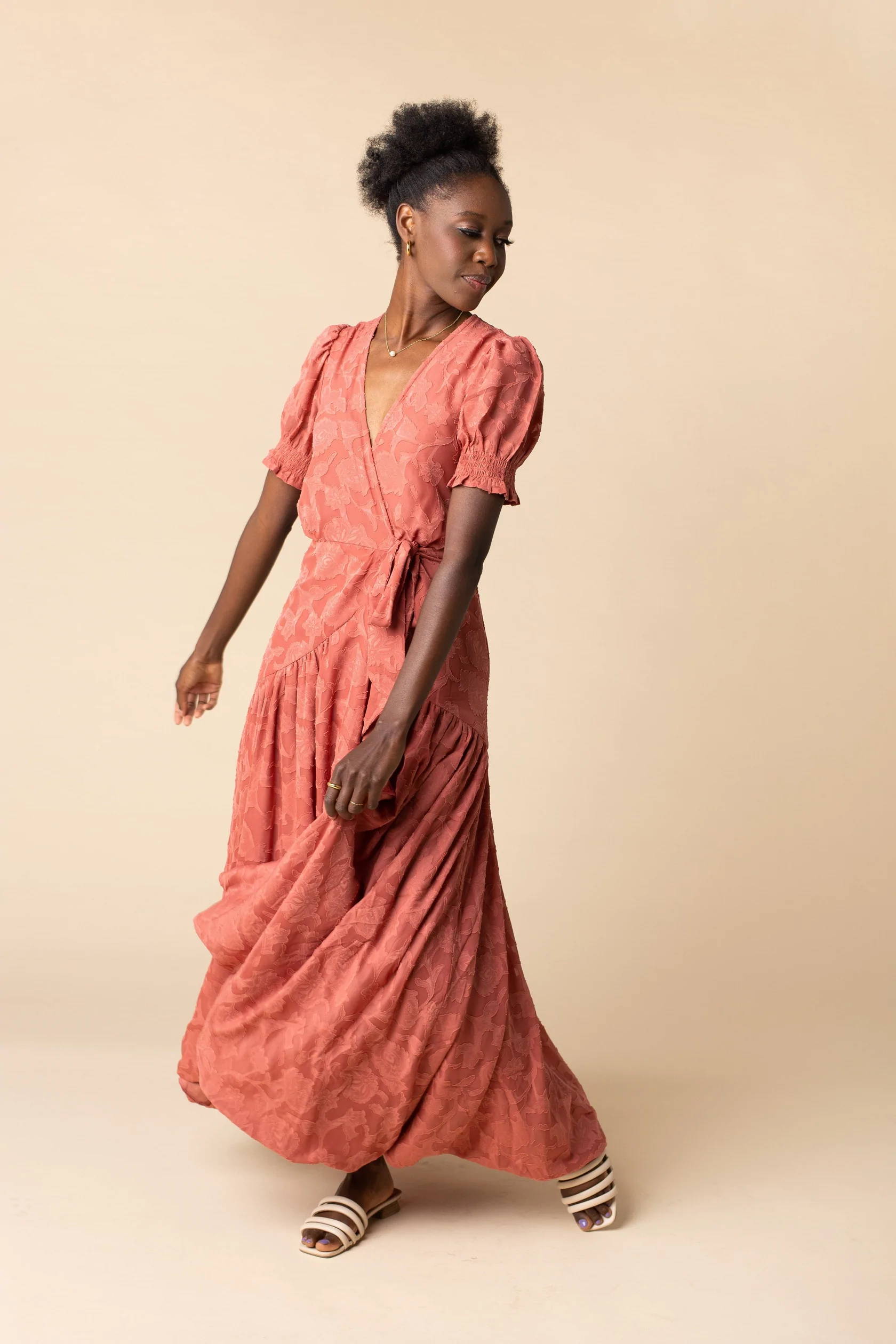 A woman poses in an orange floor-length fall dress