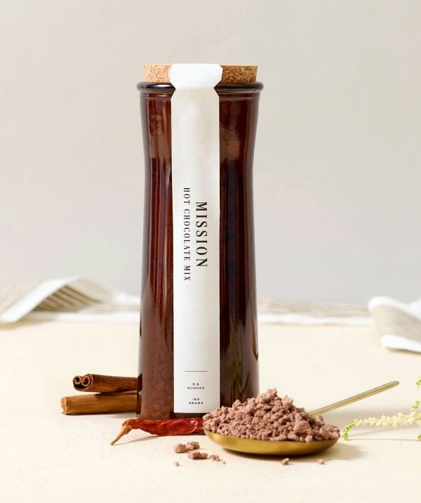 A glass jar with a cork lid and spices on a table.
