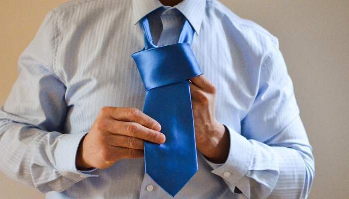 Man tying a blue necktie