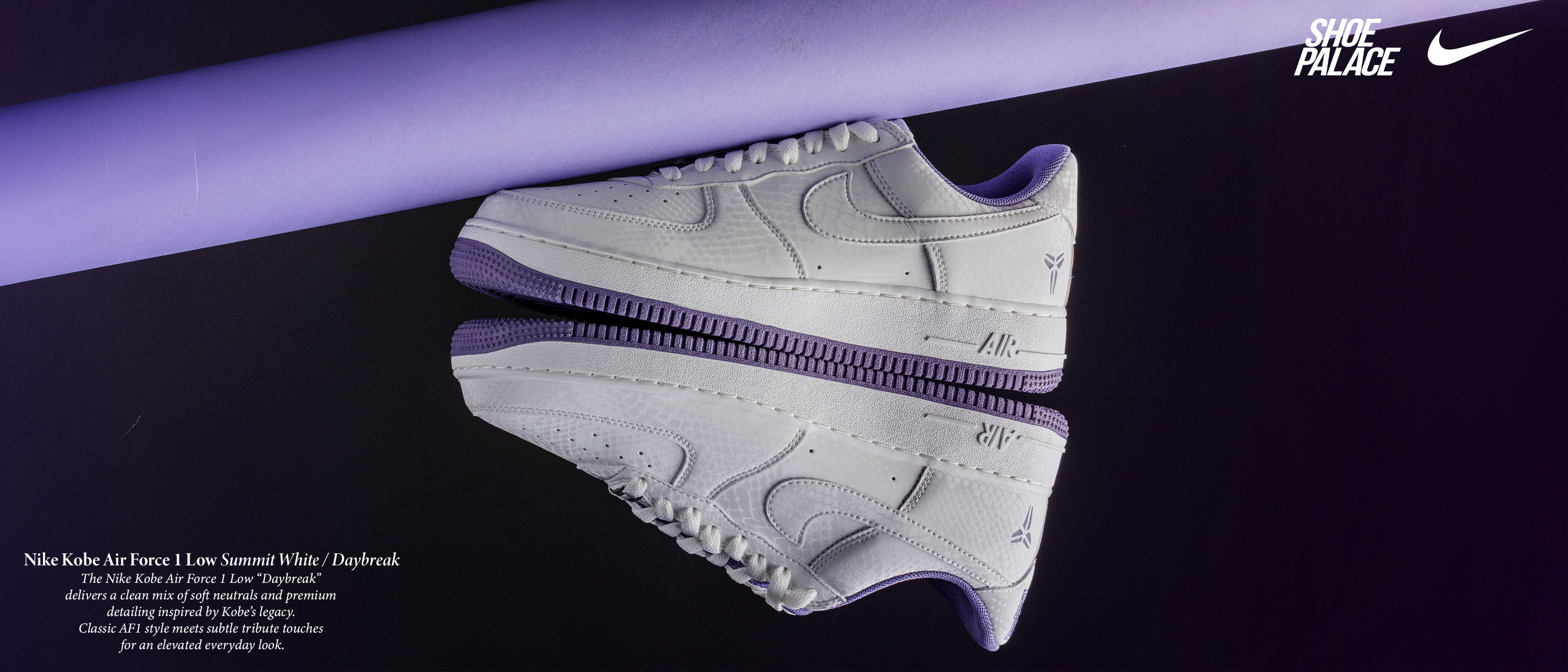 A white Nike sneaker reflected on a dark surface with purple lighting.