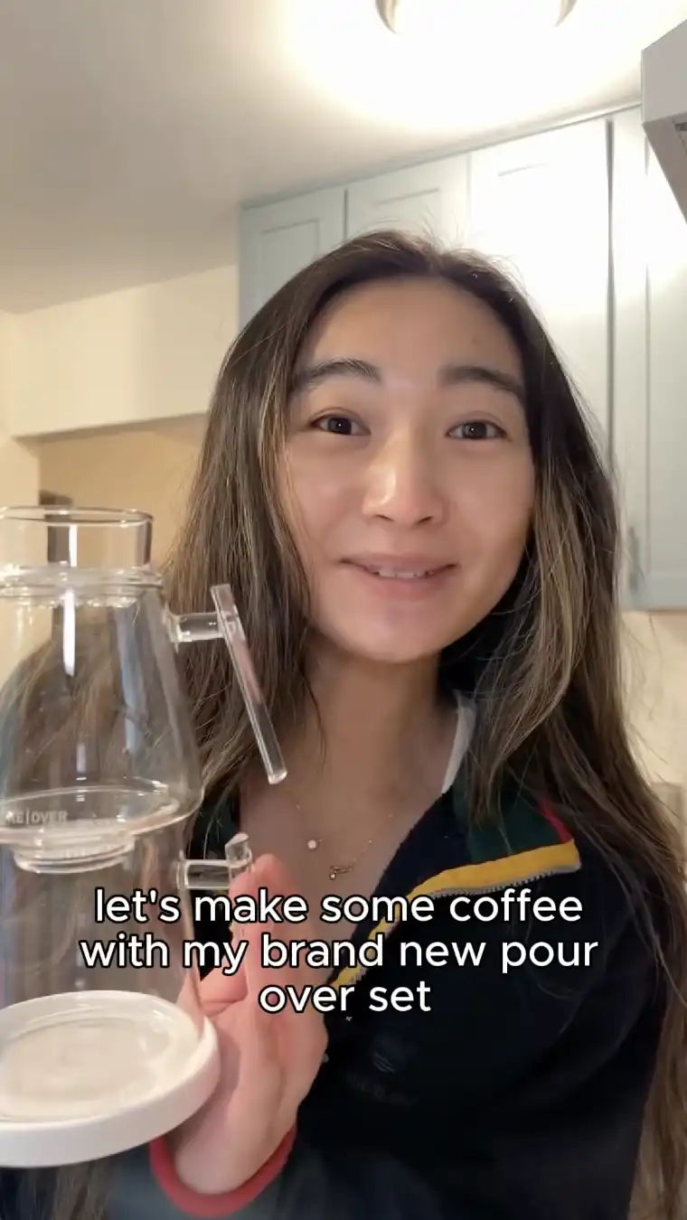 Person holding a coffee pour-over set, smiling and promoting coffee making.