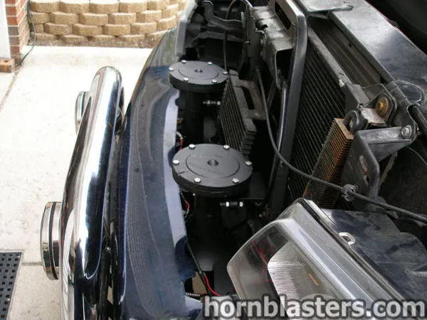 Front-end close-up showing Nathan AirChime K3 horn components mounted behind the grille and bull bar on Jerry's Silverado, install photo 4