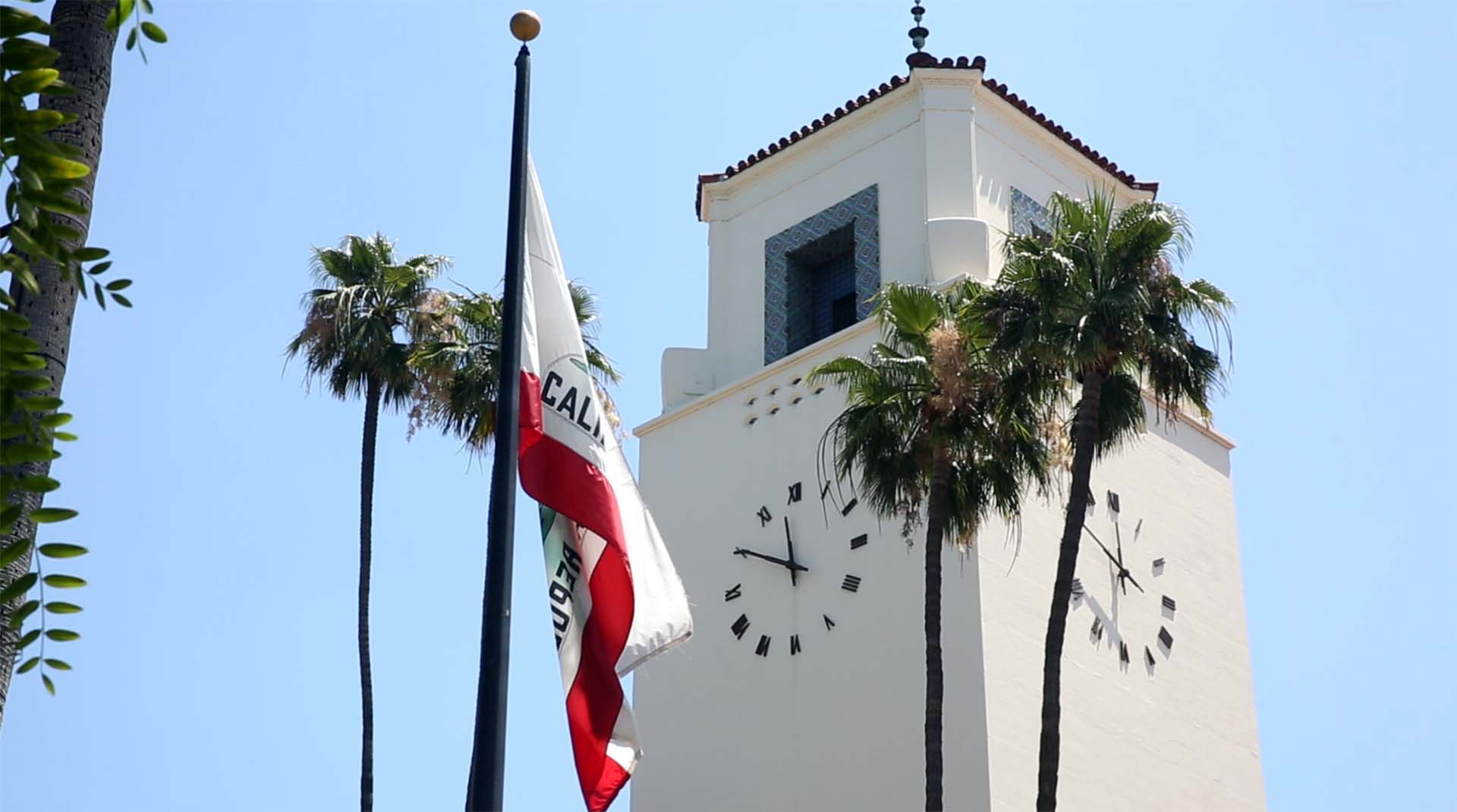 The California flag and palm trees in front of the clock tower at Los Angeles' Union Station.