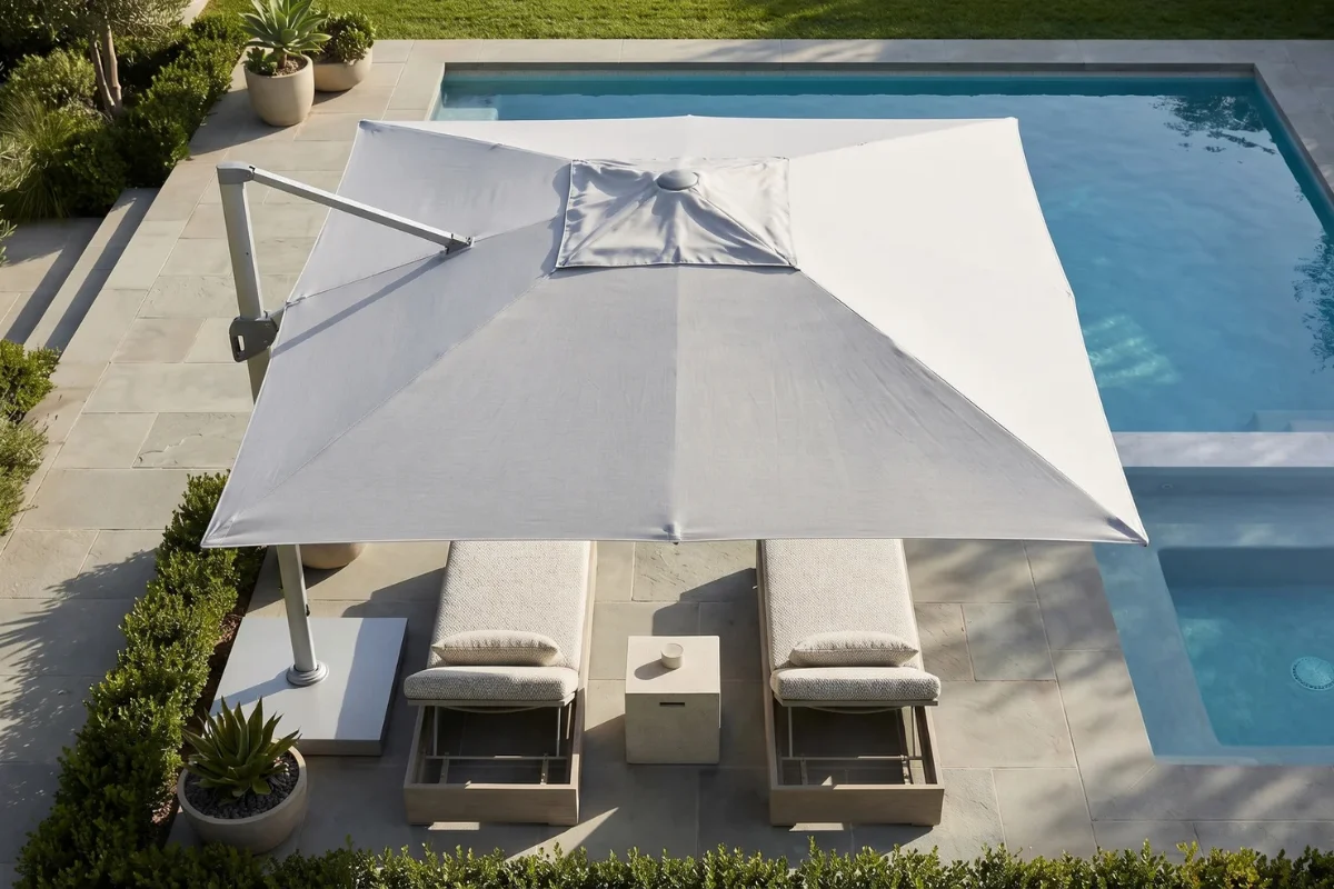 Overhead view of a large cantilever umbrella creating shade for poolside chaise lounges, demonstrating effective sun protection for luxury outdoor living spaces