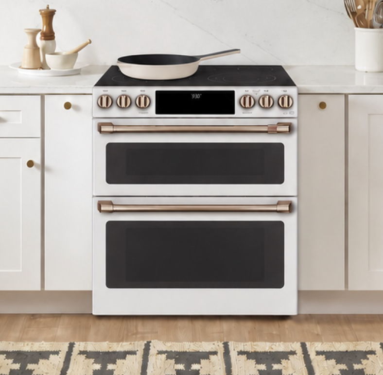 A modern white oven with two oven doors and a frying pan on top.