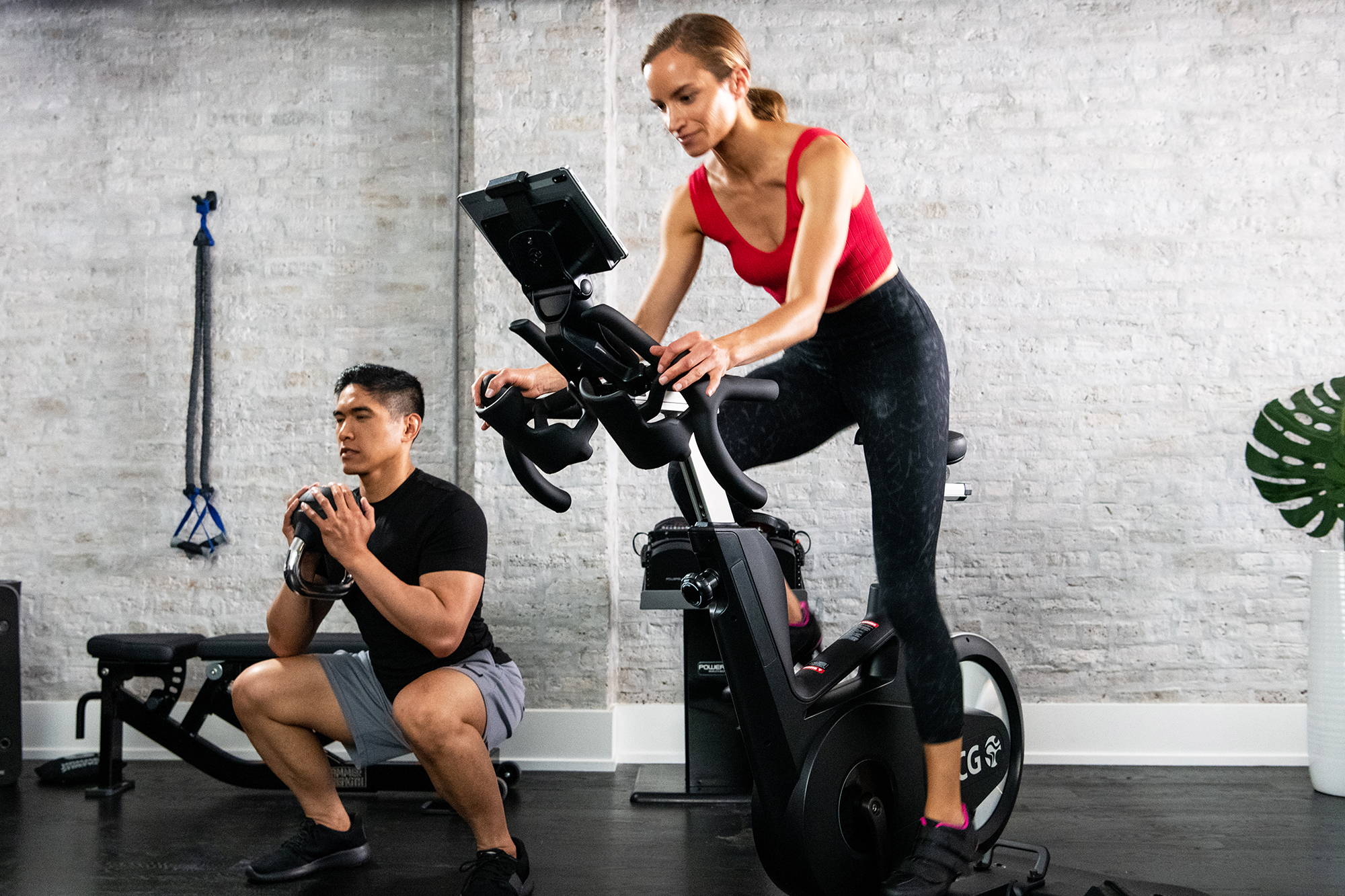 Female riding Ride CX with man exercising next to her at home