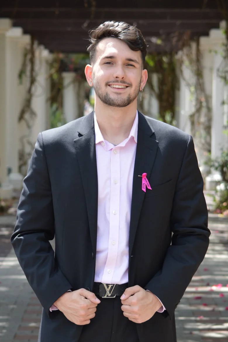 Young man in a suit standing confidently in a floral archway.
