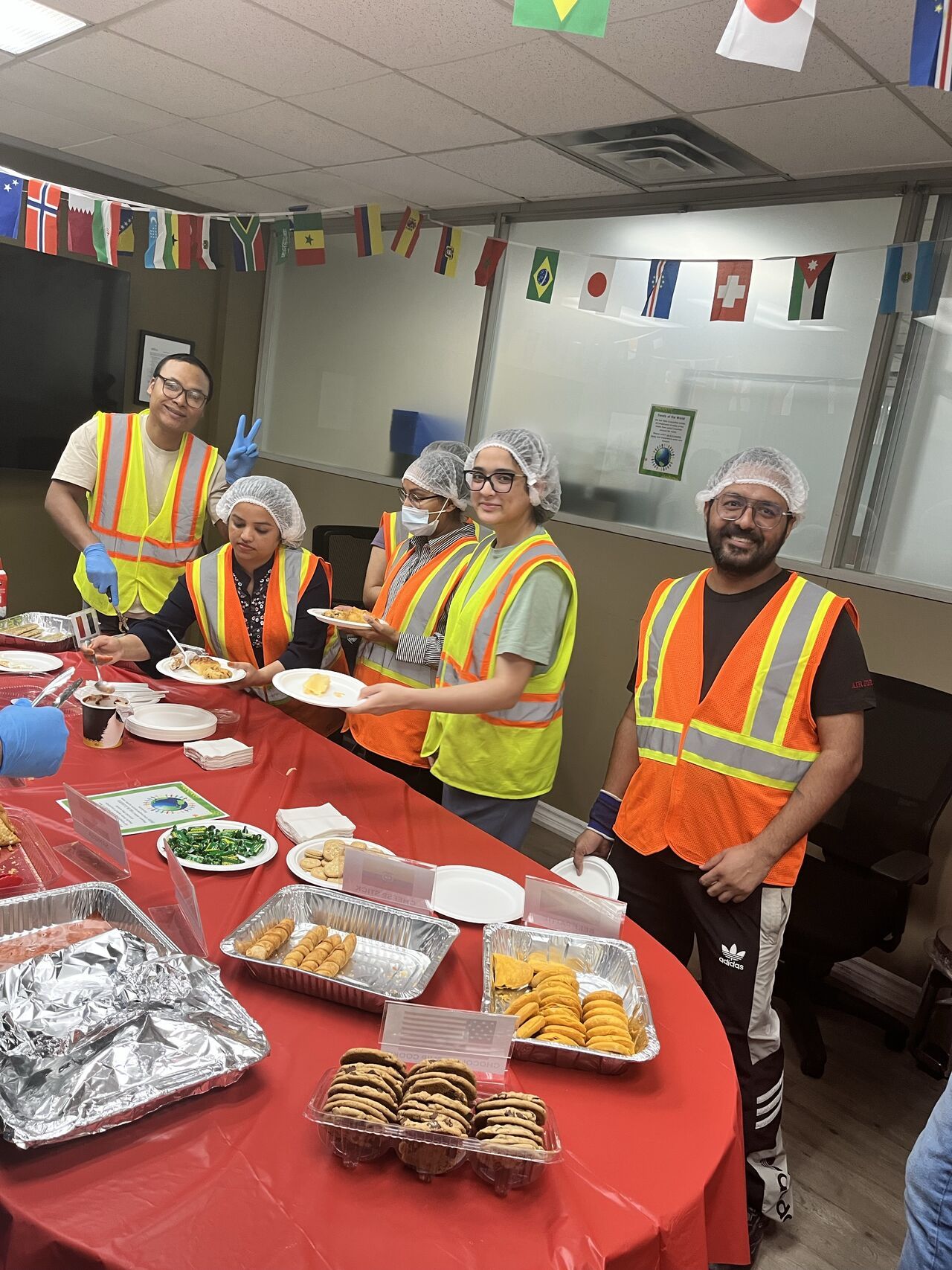 Group of people in safety vests serving food at a communal table.