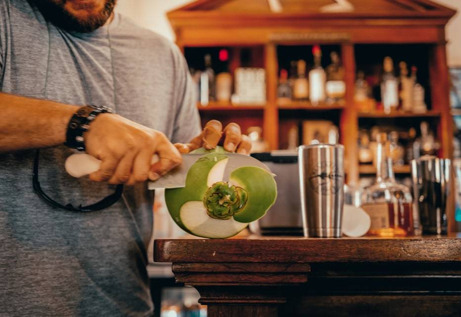 Man slicing open a coconut on the bar
