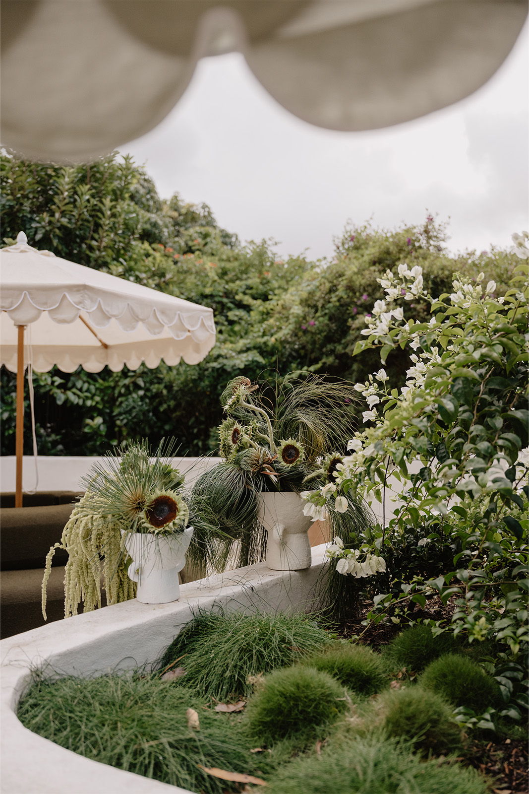 Lush garden with plants, white flowers, and a shaded seating area.