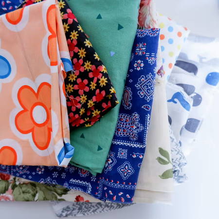 a pile of different fabrics for sewing