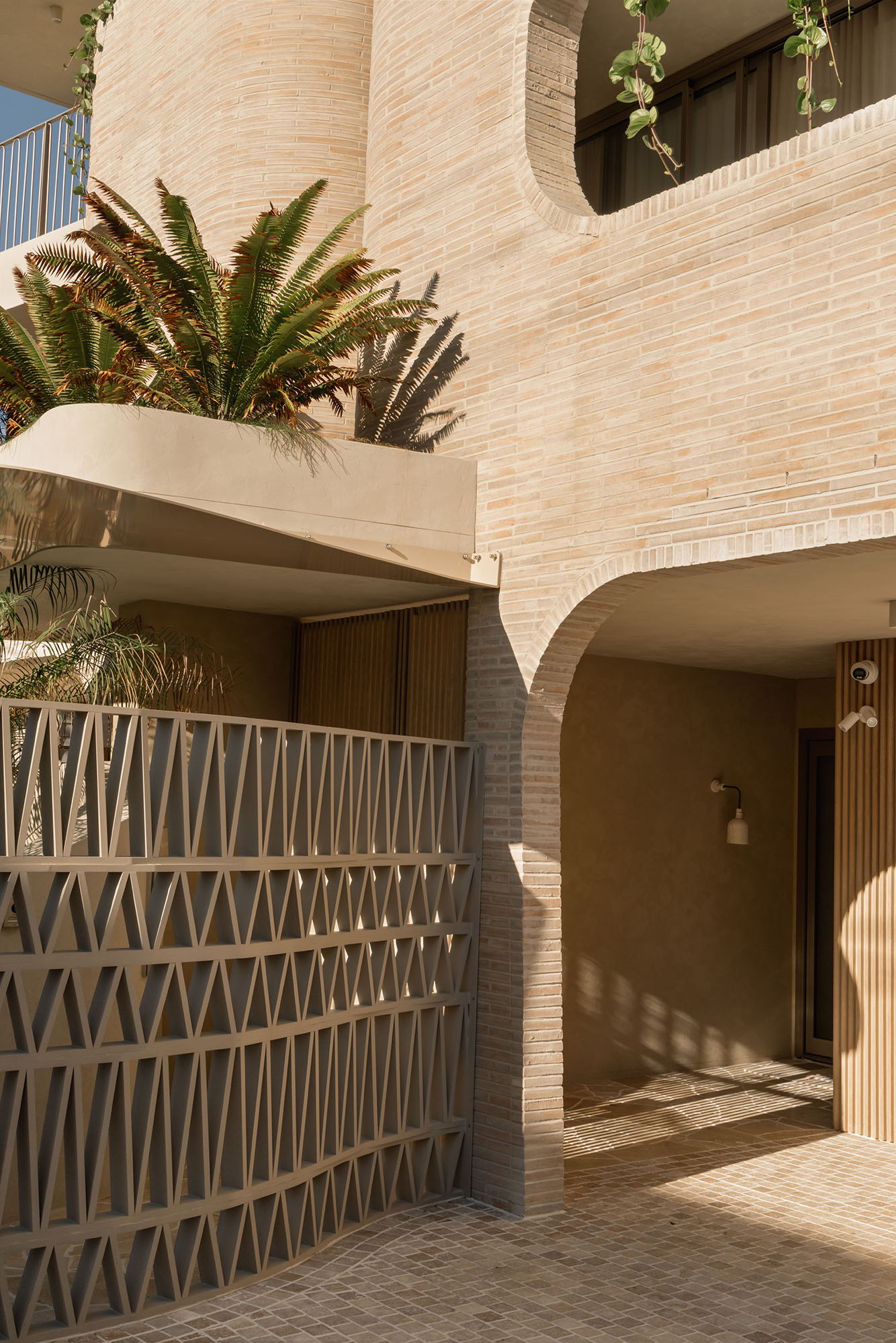 Modern architecture featuring textured walls, plants, and a decorative gate.