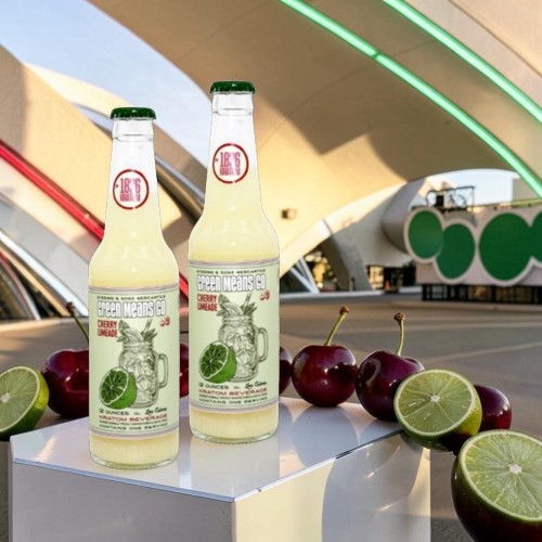 Two bottles of lime soda with apples and limes in the foreground.