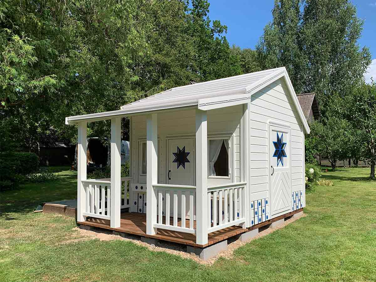 Wooden Playhouse in white and blue color with white metal roof, wooden terrace and doors with cornflower-shaped window by WholeWoodPlayhouses